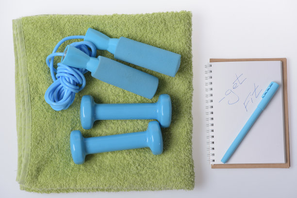 哑铃和跳绳躺在白色背景的毛巾上图片下载