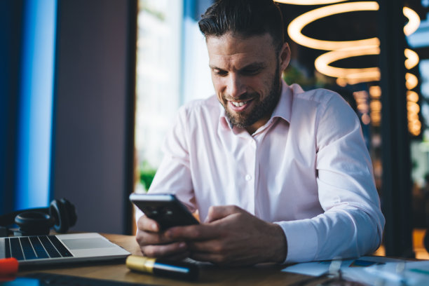 快乐的男人在现代办公室使用智能手机图片下载