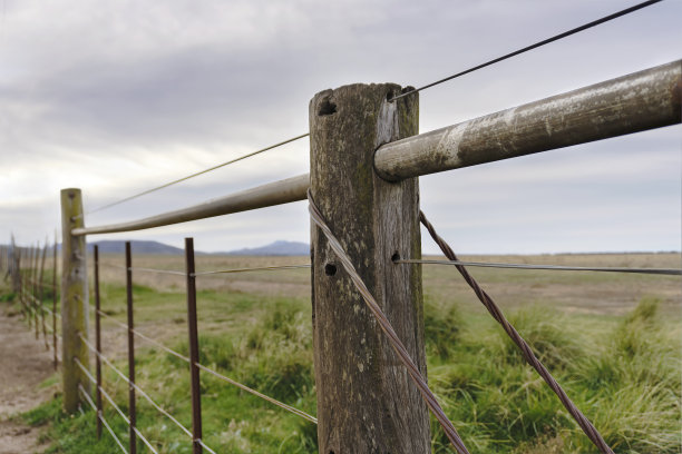 以铁丝栅栏和田野为背景的一根杆子特写的乡村景观图片下载
