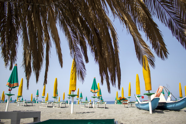 热带海滩全景。带棕榈叶的沙滩伞。在意大利海滩度假。假期的概念。图片下载