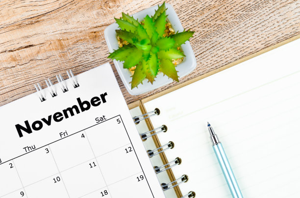 2022年11月的台历和木制背景用笔打开的日记本。图片下载