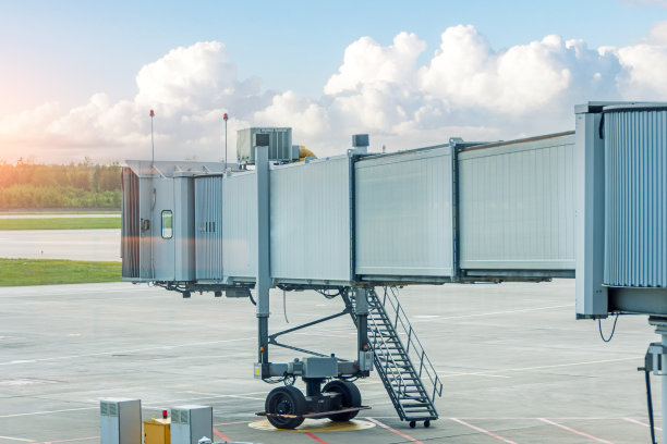 空空如也的飞机停在机场停机坪上的客运天桥上，映衬着美丽的天空。图片下载