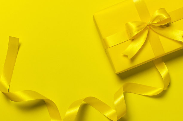 节日的概念。黄色礼品盒蝴蝶结，节日彩带在明亮的黄色背景平铺俯瞰副本空间。惊喜，生日礼物，母亲节，3月8日，圣诞节。祝贺图片下载