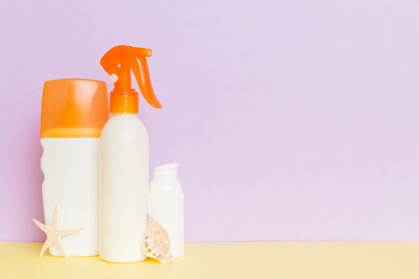 海滩配件。保湿防晒乳液瓶的UVB皮肤保护在夏天与彩色背景的贝壳。用拷贝空间模拟图片下载