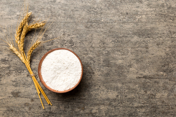 将小麦粉平铺于木碗中，彩色底色上点缀着小麦穗。世界小麦危机图片下载