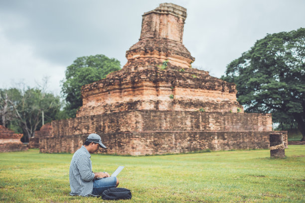 在泰国素可泰历史公园工作和使用笔记本电脑的游客。假期和假期概念图片下载