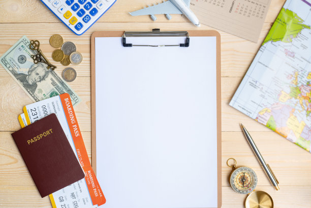 航班行程/长周末，旅行计划计划的概念:俯视图/平铺的白色空白/空白纸在剪贴板，美元货币，硬币，护照，登机牌，飞机，木桌上的地图图片下载