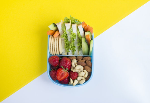 彩色背景上蓝色盒子里的学校午餐俯视图。副本的空间。特写镜头。图片下载
