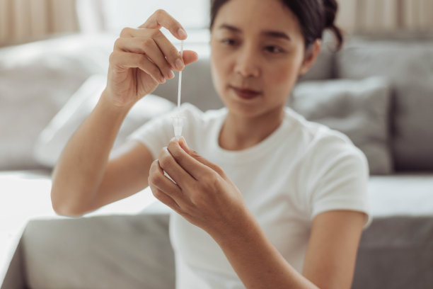 年轻女子在家使用抗原试剂盒进行新冠病毒自测图片下载