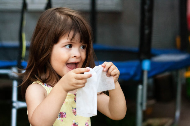 这个小女孩正在用纸巾(手帕)擦鼻子。图片下载
