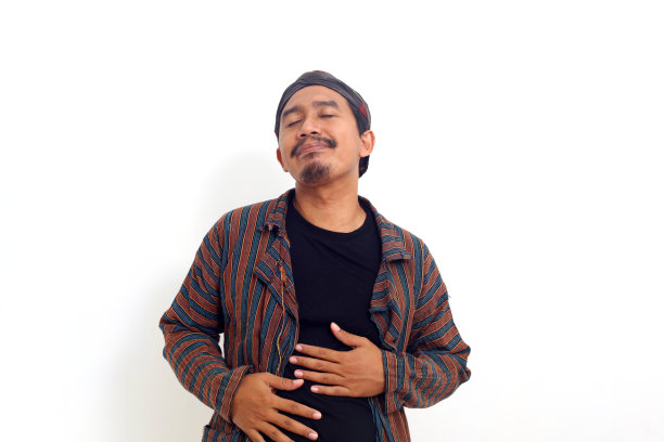 亚洲男人站着摸肚子，感觉很饱，很满足。孤立在白色背景上图片下载