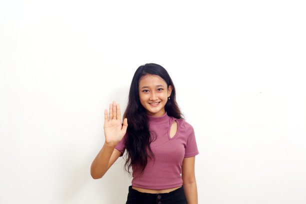 微笑的亚洲年轻女孩站在与她的手停止手势。孤立在白色背景上图片下载