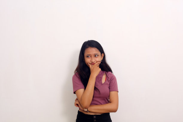 亚洲女孩与手下巴困惑的表情孤立在白色背景图片下载