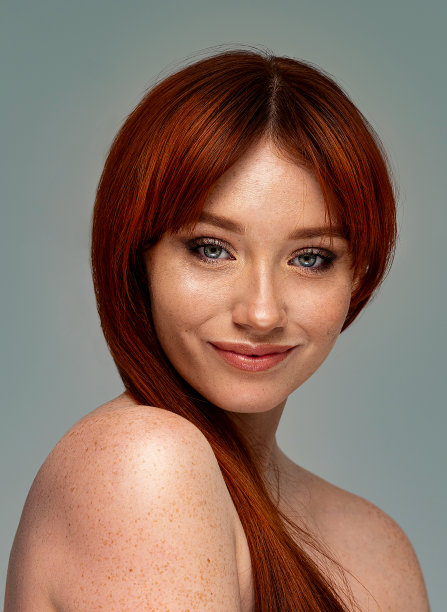 健康的面部皮肤护理。美丽的女孩化着精致的妆容，红色的头发微笑着看着镜头。副本的空间。图片下载