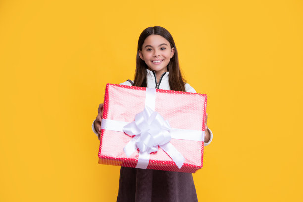 积极的女孩与礼物盒子在黄色的背景图片下载