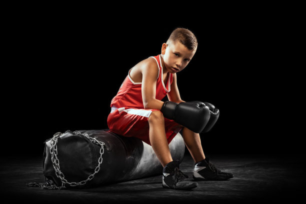 初学拳击的少年，在黑暗的背景下独自训练。运动、运动、学习、成就、生活方式的概念。图片下载