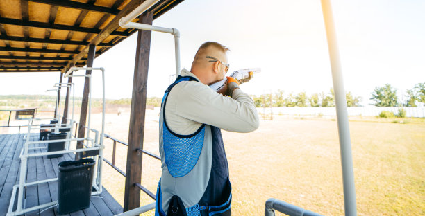 戴着墨镜，穿着步枪背心的成年男子正在练习射击。年轻有经验的男性户外瞄准枪。图片下载