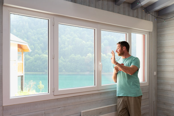 微笑着的男人透过他公寓的窗户向我打招呼。图片下载