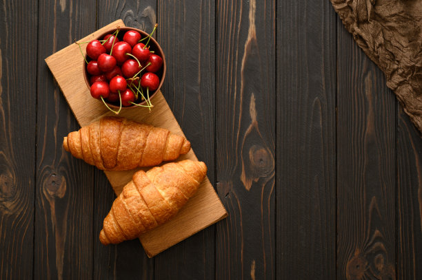 牛角面包配樱桃，背景质朴。图片下载