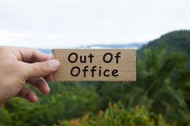 手持写有文字的木制横幅-离开办公室。有山和山的背景。图片下载