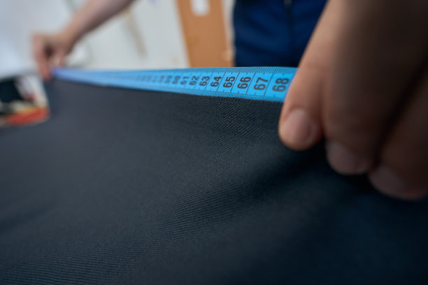 设计师在桌子上测量深色织物的长度图片下载