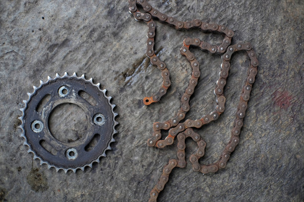 被油污和锈迹覆盖的马达车轮和链条的旋转齿轮图片下载