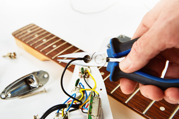 电吉他修理:一名男子在他的工作台上拆开了一把吉他的电子部剪断了一根电线图片下载
