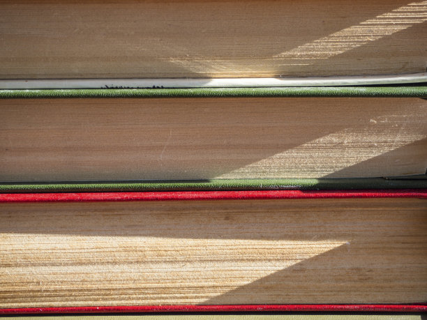 近景将泛黄边缘的旧书书页叠放，可用作背景、纸张纹理的书籍图片下载