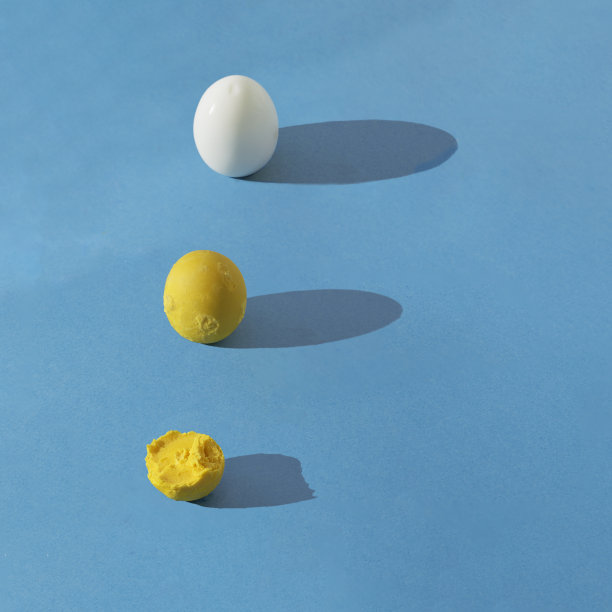 蛋白和整个和半吃的蛋黄排成一排，在蓝色背景上有长长的阴影。正方形合成与复制空间。健康的早餐概念。图片下载