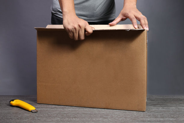 灰色的桌子上放着纸板箱的笔记本电脑。图片下载