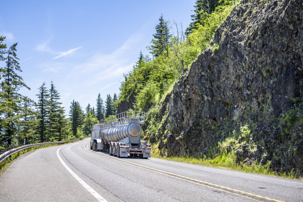 带加强筋的锥形肥料散装半挂车运输货物的白色工业大钻机半挂车在山路上转弯图片下载