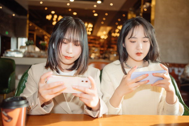 两名女性正在咖啡店玩手机游戏图片下载