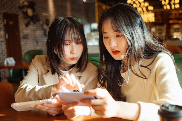 两名女性正在咖啡店玩手机游戏图片下载