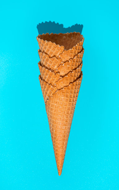 在强光下，蓝色背景下的一堆华夫饼冰淇淋蛋筒。图片下载
