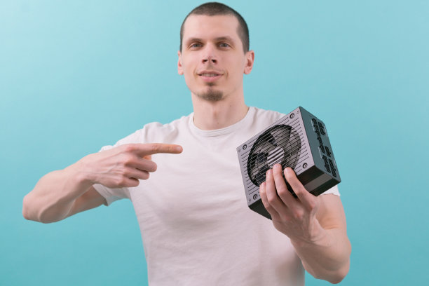 蓝色背景上，一名男子用手指着电脑电源。对象。面板。事业单位。能量。电压。精力充沛。电源。源。热量。连接器。设备。接口。系统图片下载