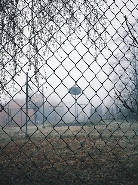 在一个雾蒙蒙的日子里，在一个废弃的篮球场上的栅栏后面图片下载
