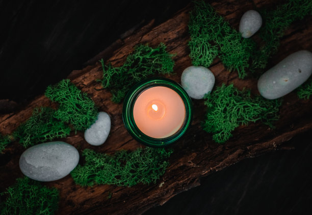 黑色背景下，绿蜡烛、苔藓和树皮上的石头。图片下载