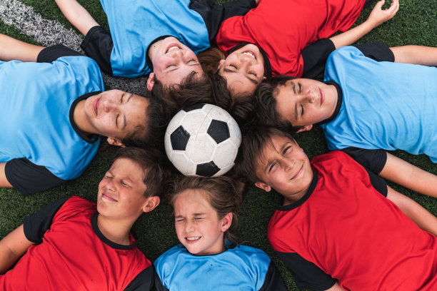 足球队的孩子们躺成一圈，中间有一个足球图片下载
