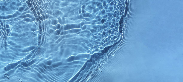 蓝色的水纹理，蓝色的水面有环纹和涟漪。水疗概念背景。飞溅化妆品保湿水胶束爽肤水或乳液蓝色图片下载