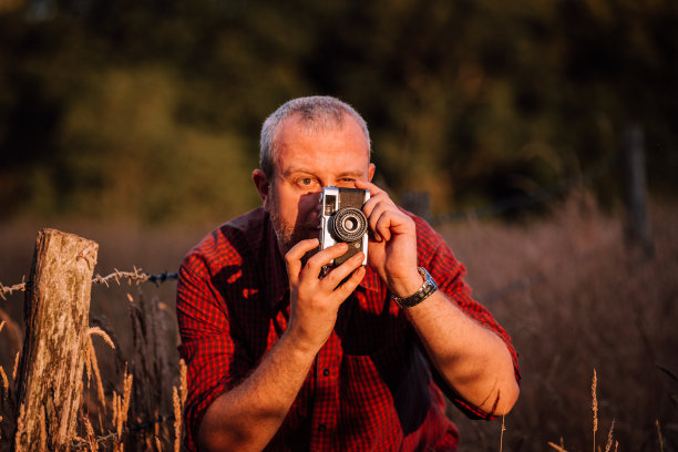 摄影师在大自然中使用老式胶片相机拍摄日落图片下载
