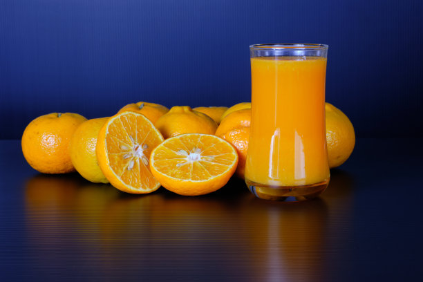 一杯橙汁和一组新鲜的橘子在黑色的背景。图片下载