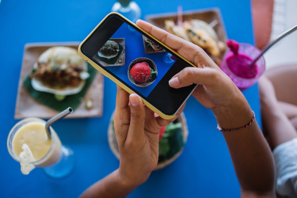 裁剪的女性视频博主使用手机主相机点击媒体图片和创建内容分享到美食博客，美食摄影墨西哥美食在拉丁小酒馆咖啡馆的午餐图片下载