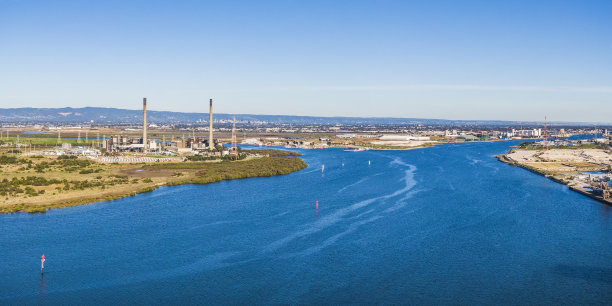 高空阳光全景燃气发电站位于敏感河口，以城市和山丘为背景图片下载
