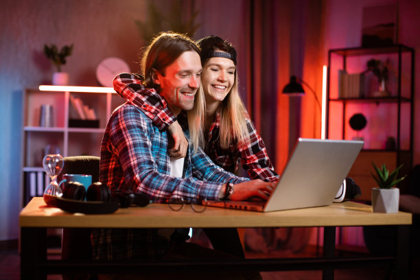 两个年轻的同事晚上坐在办公室里微笑着聊天。图片下载