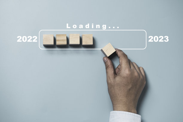 手放木制立方体块装载和更新进度从2022年到2023年，准备圣诞快乐和新年快乐的概念。图片下载