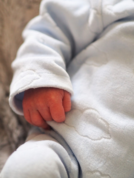 一个小男孩的手的特写。婴儿穿着蓝色的睡衣。图片下载