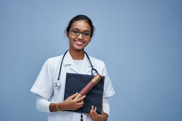 穿着白大褂、手持听诊器的女医生。图片下载