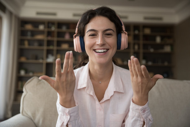 积极的女学生戴着粉色耳机在视频通话，图片下载