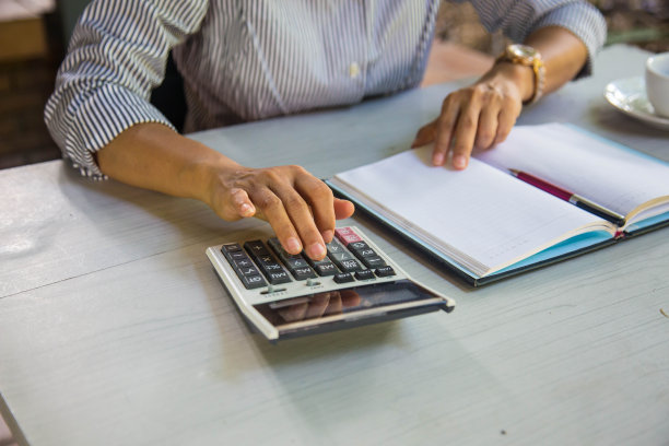 在家庭办公室的木桌上使用计算器财务的商业女性图片下载