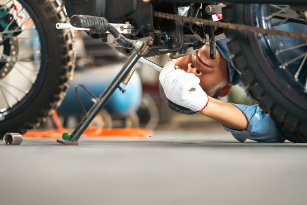 车库或车间的机械师在维修过程中检查经典摩托车的照片。图片下载